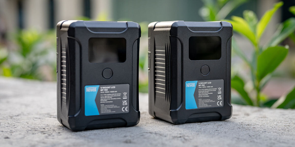 Akumulator NEWELL 14000 mAh do BP-190 LCD V-Mount, przegrzanie, przeładowanie, efekt, pamięci, akumulatory stoją pionowo frontem lewo skos na murku, w tle roślinność