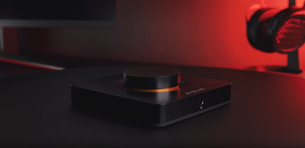 Wzmacniacz słuchawkowy JDS LABS Element III Boosted Copper Ring wysoka jakość dźwięku i wzmocnienie, wzmacniacz słuchawkowy postawiony na czarnym blacie obok monitora i słuchawek