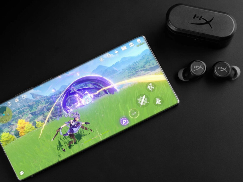 Słuchawki HYPERX Cirro Buds Pro tryb gamingowy niskie opóźnienia 90 ms dla graczy Nintendo Switch PC, etui ładujące wraz z słuchawkami oraz smartfonem na czarnym blacie