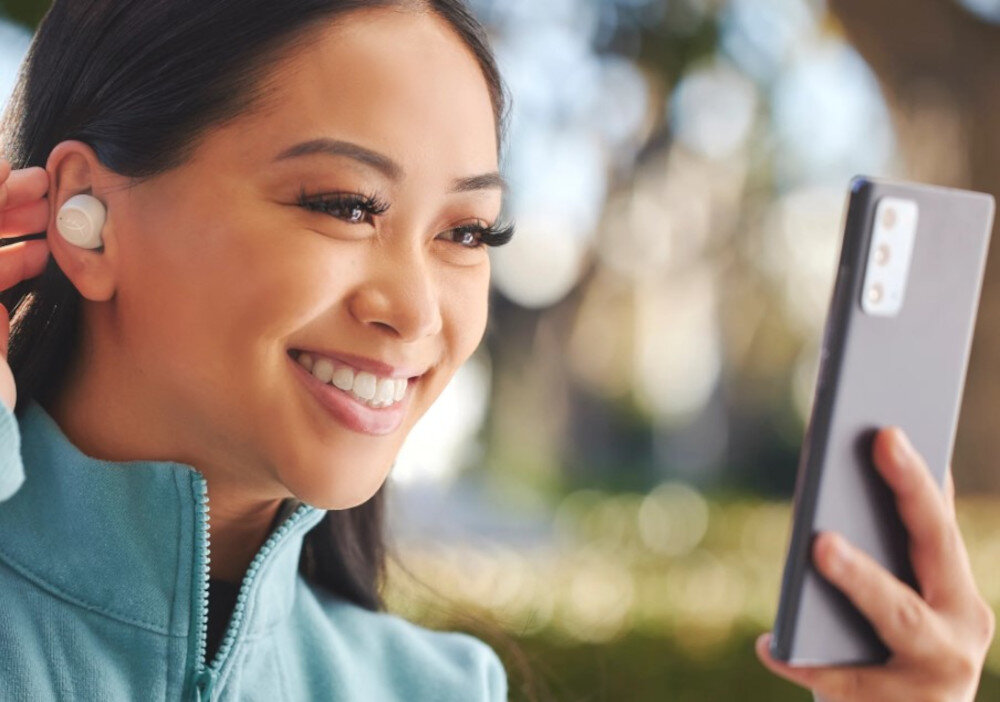 Słuchawki HYPERX Cirro Buds Pro aktywna redukcja szumów Hybrid ANC cztery mikrofony czysty dźwięk, osoba z założonymi słuchawkami trzymająca telefon