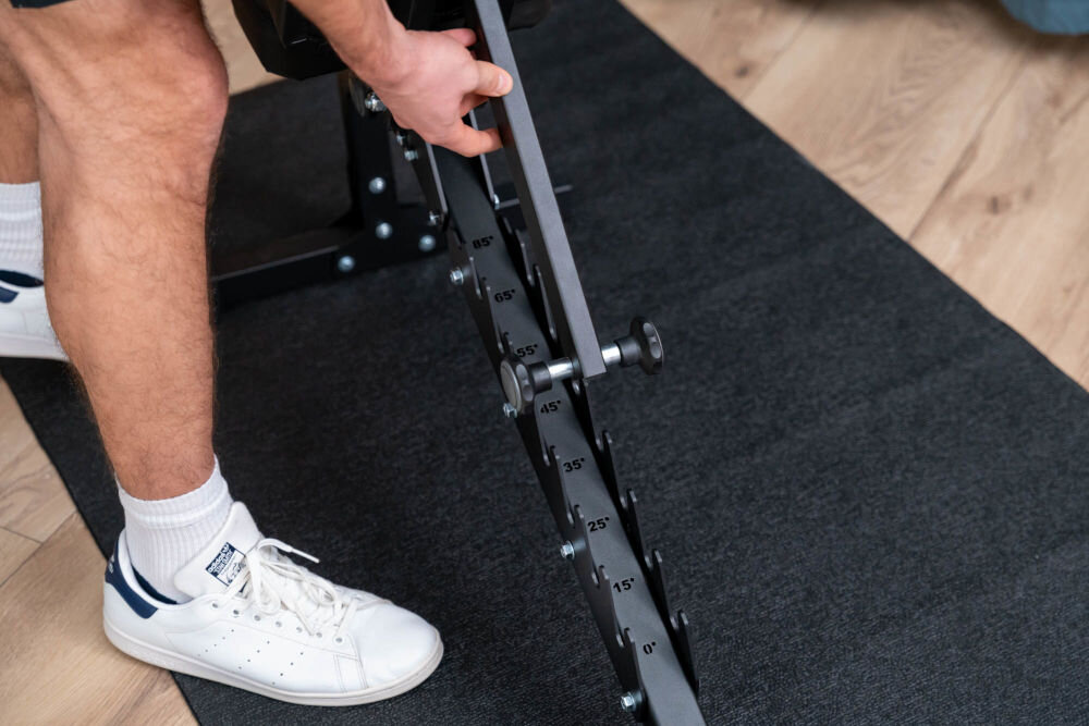 Ławka do ćwiczeń S-LINE ELLI BF300 regulcja oparcia 9-stopniowa skala od -22 do 75 stopni obciazenie do 300 kg Zbliżenie na mechanizm regulacji kąta nachylenia oparcia ławki treningowej z widocznymi stopniami od 0 do 85.