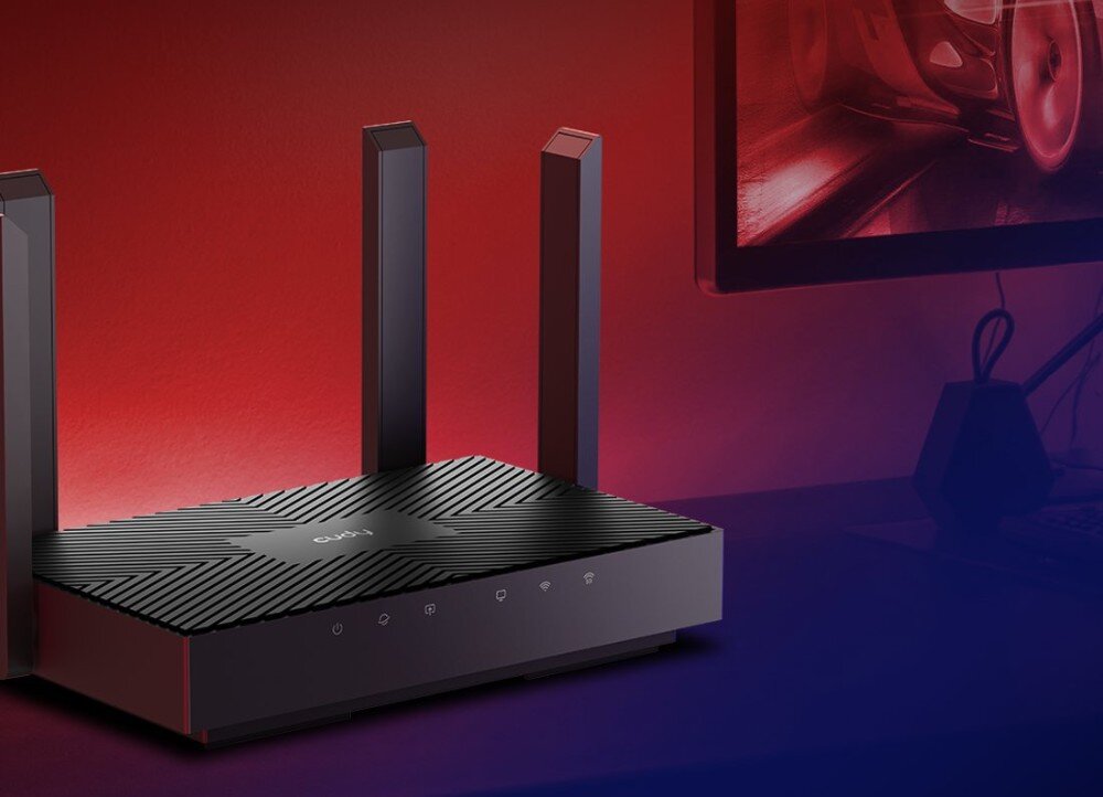 Router CUDY WR3000 Router z czterema antenami ustawiony na biurku obok monitora z dynamiczną grafiką. Tło ma czerwono-niebieskie gradientowe oświetlenie, łączność Wi-Fi 6, pasma, prędkość