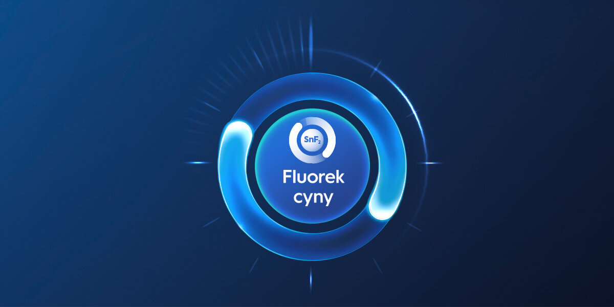Grafika przedstawia niebieski okrąg z napisem \'Fluorek cyny\' oraz symbolem \'SnF2\' w centrum. Tło jest ciemnoniebieskie z delikatnymi promieniami świetlnymi wokół okręgu.