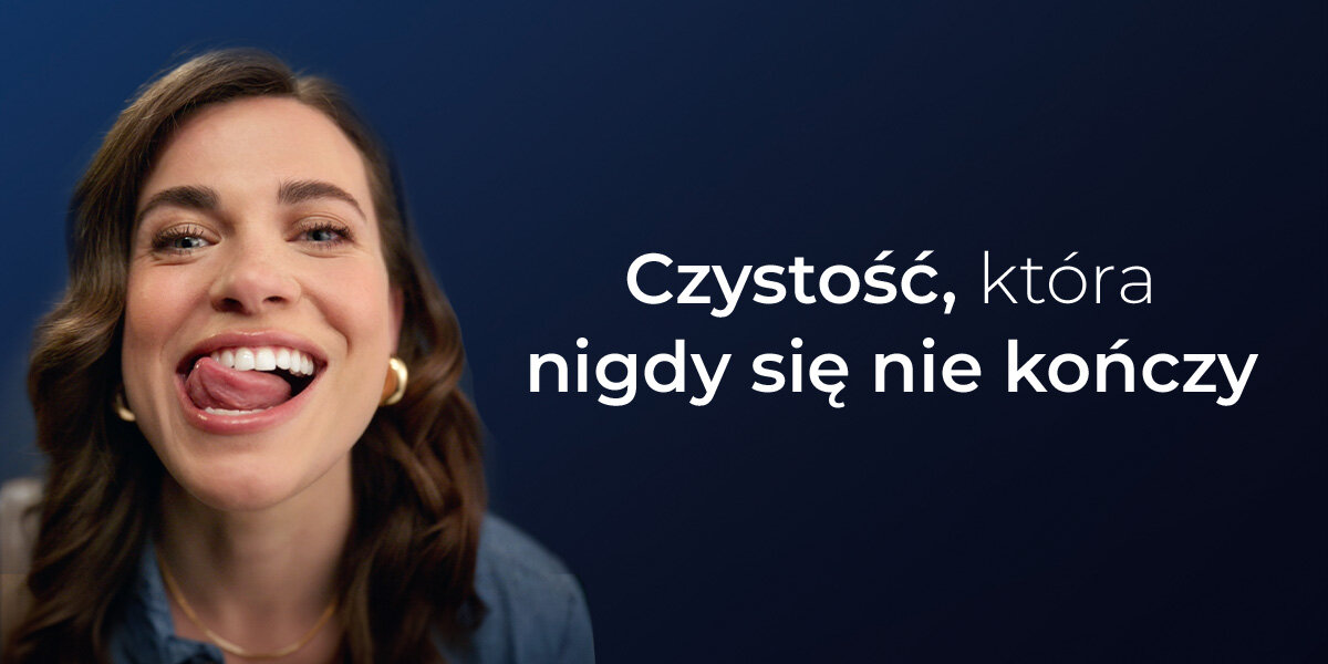 Osoba z uśmiechem na twarzy wystawia język. Obok widoczny jest tekst: \'Czystość, która nigdy się nie kończy\'.