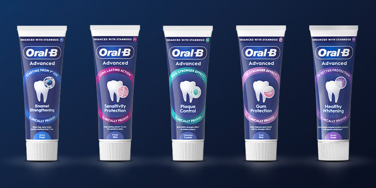Na obrazie widoczne są tubki past do zębów Oral-B Advanced z różnymi wariantami: Enamel Strengthening, Sensitivity Protection, Plaque Control, Gum Protection i Healthy Whitening. Każda tubka ma niebieskie tło i białe napisy, a na środku znajduje się grafika zęba z różnymi symbolami.