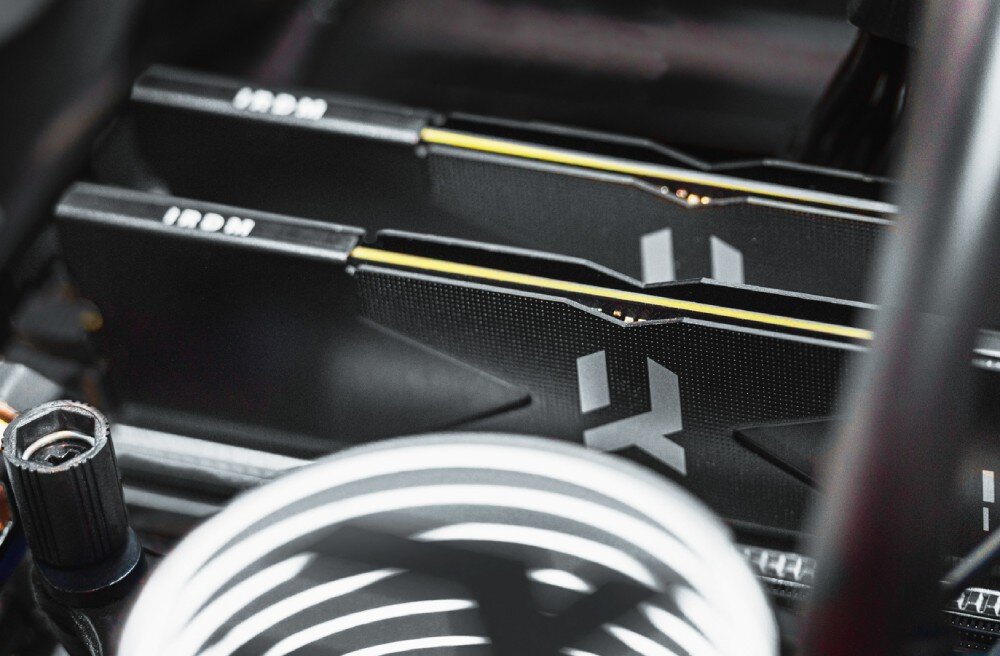 Pamięć RAM GOODRAM IRDM DDR5 Zbliżenie na zamontowane w komputerze moduły pamięci z widoczną fakturą radiatora oraz fragmentem białego elementu chłodzenia na pierwszym planie, parametry, podkręcenie, profile Intel XMP i AMD EXPO