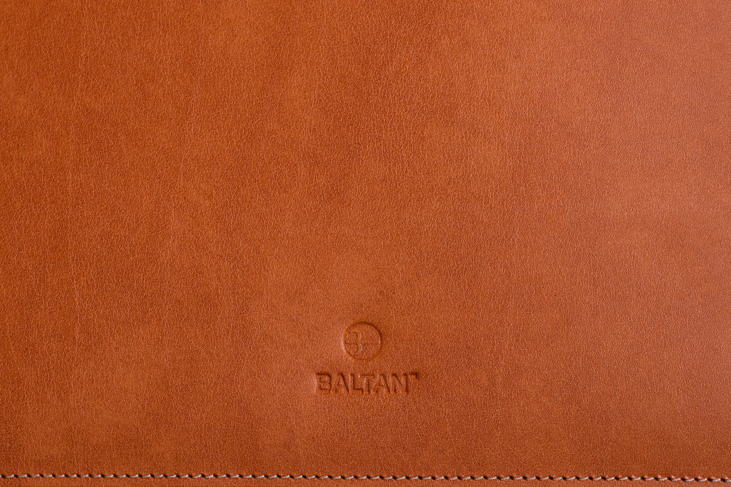 Brązowe etui wykonane z gładkiego materiału, z wytłoczonym logo \'BALTANT\'.