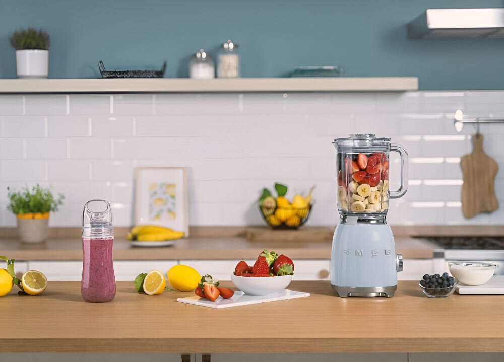 Blender kielichowy SMEG BLF03BLEU blender w kolorze niebieskim stoi na blacie wewnątrz dzbanka znajdują się owoce Silnik o mocy 800 W do 18000 obrotów na minutę minimum 9000 obr./min cztery poziomy prędkości trzy tryby Pulse dostosowanie intensywności pracy aksamitne koktajle smoothie gęste zupy chłodne mrożone koktajle optymalne rezultaty