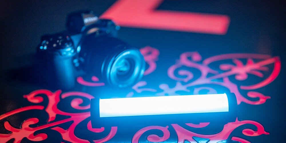 Lampa LED Newell RGB Kathi Nano Pro - leży włączona na podłożu z czerwonym wzorem