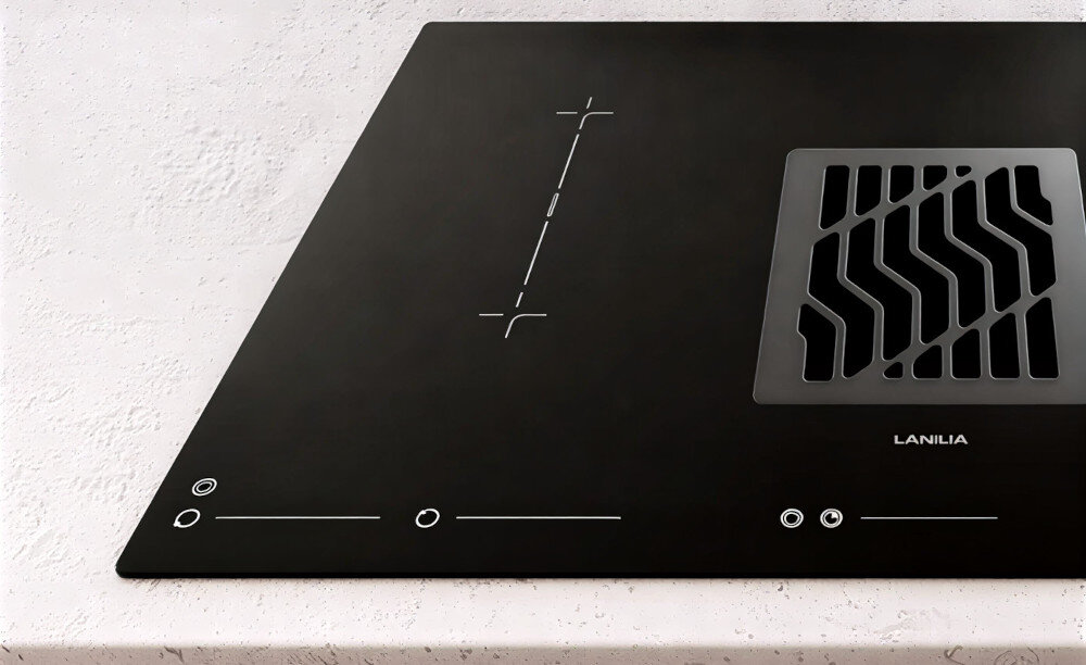 PŁYTA INDUKCYJNA LANILIA VILIO 80.1 Zdjęcie przedstawia fragment płyty grzewczej z wbudowanym wyciągiem, ustawionej na jasnym, kamiennym blacie. Widoczne są oznaczenia jednego z pól grzewczych oraz część kratki wyciągu, co podkreśla przejrzysty i funkcjonalny układ urządzenia zabezpieczenie przegrzanie bezpieczeństwo automatyczne wyłączenie