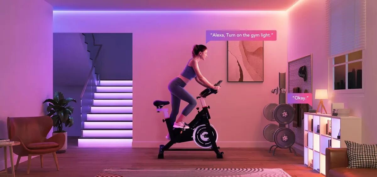 Przedłużenie taśmy LED GOVEE H100E 1 m Wi-Fi, 24V, klej, 10m, montaż, Kobieta na rowerku z fioletowym oświetleniem LED w pokoju fitness.
