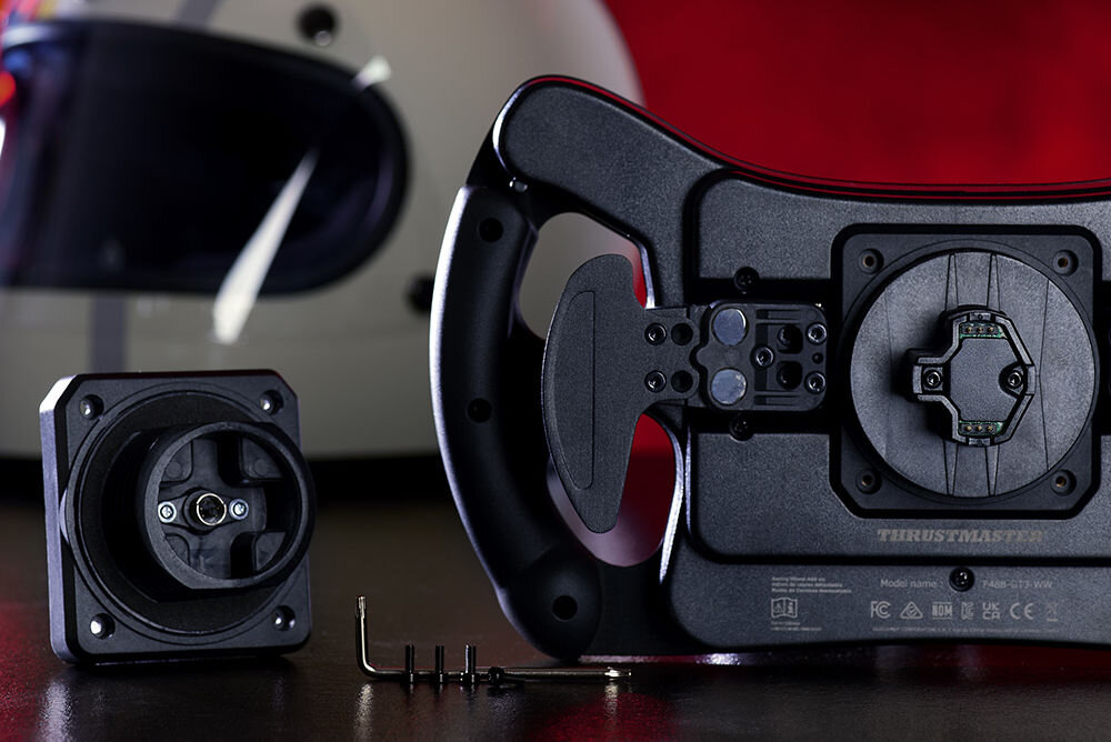 Kierownica THRUSTMASTER Ferrari 488 GT3 Wheel Add-On prezentacja urządzenia od tyłu i jego łopatek zmiany biegów na tle kasku i czerwonego tła czujniki magnetyczne wsparcie precyzyjnych manewrów obniża ryzyko błędów cztery konfiguracje montażu elastyczność kopasowanie