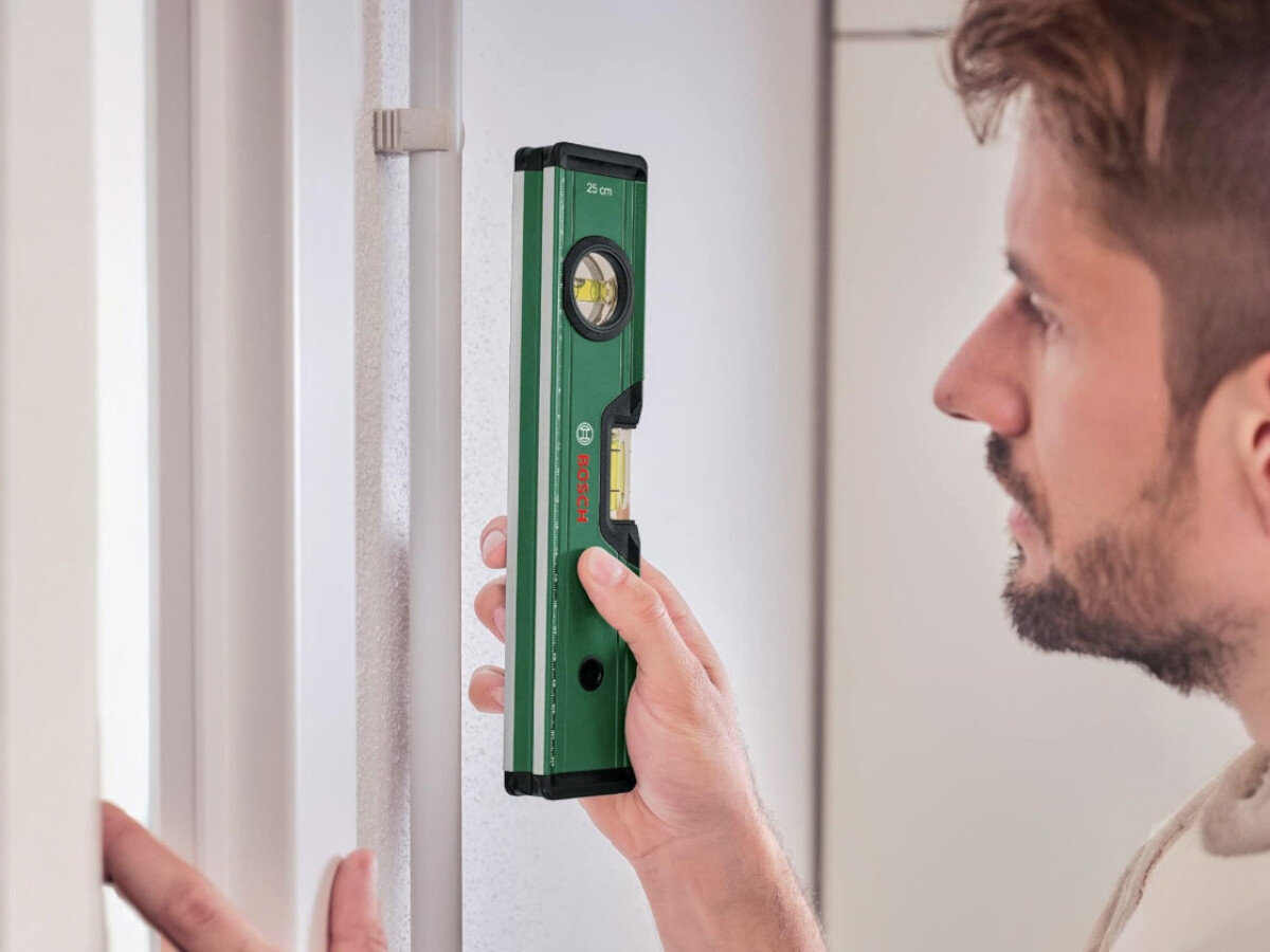 Poziomica BOSCH 1600A027PL, magnesy, libelle, odczyt, metal, mężczyzna przykłada poziomice do profilu pionowo
