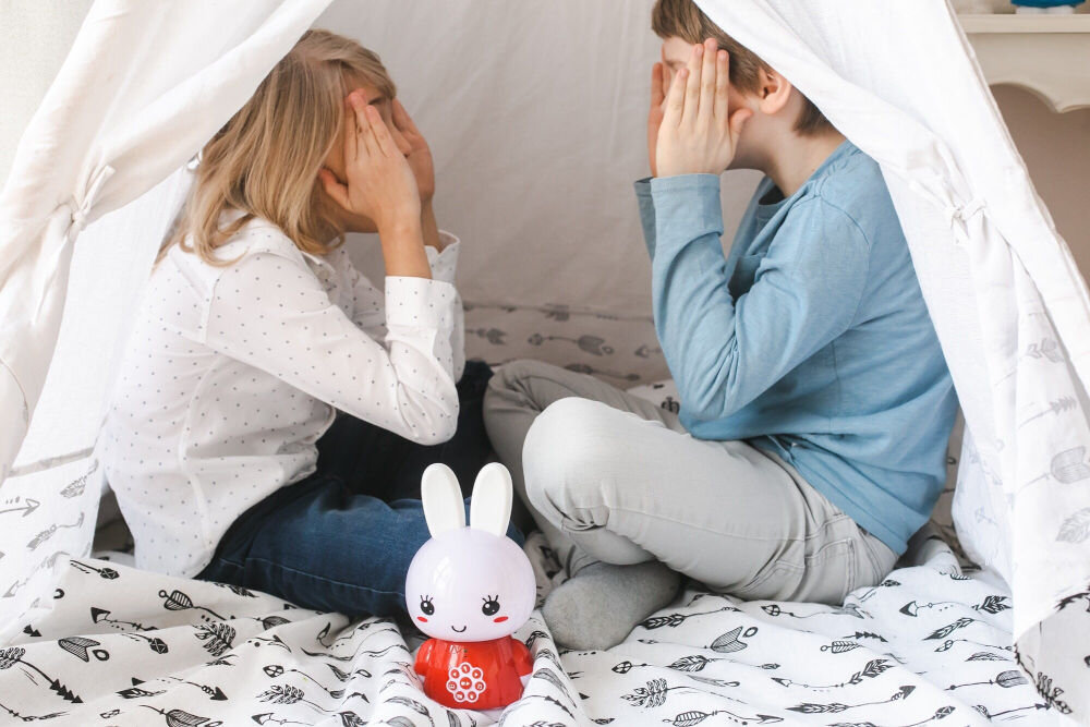 Zabawka edukacyjna ALILO Honey Bunny G6 Czerwony towarzysz Twojego dziecka, dzieci bawiące się w namiocie, a przed nimi stoi produkt