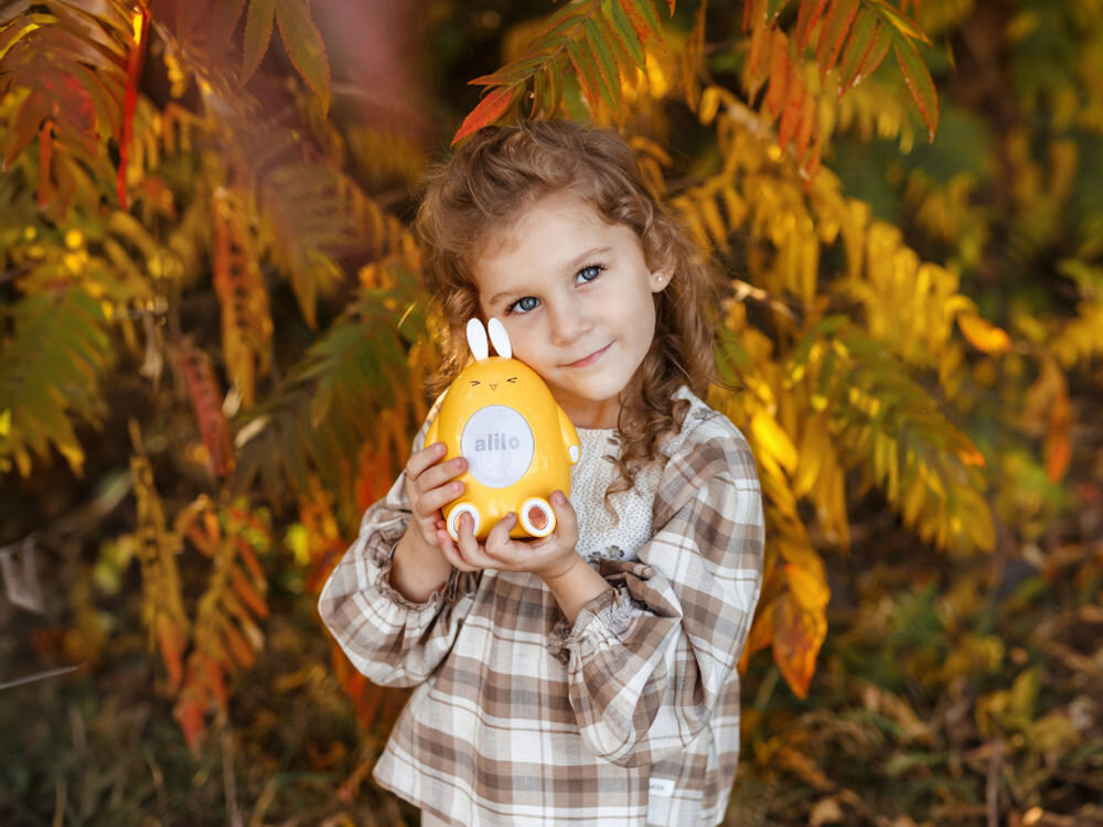 Zabawka edukacyjna ALILO Happy Bunny P1 Niebieski nauka kolorów, dzięki świecące uszka króliczka, trzy tryby zabawy z kolorami, nauka rozpoznawania kolorów, dziewczynka trzymająca produkt w wersji żółtej na świeżym powietrzu