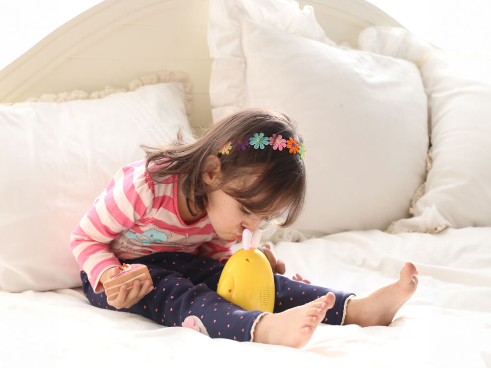 Zabawka edukacyjna ALILO Happy Bunny P1 Niebieski w trosce o dobry sen, wystarczy pogłaskać głowę króliczka, aby włączyć kołysankę, delikatne dźwięki kołysanek, 
					dziewczynka siedząca na łóżku, produkt w wersji żółtej