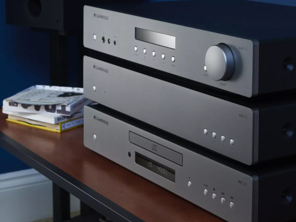 Odtwarzacz sieciowy CAMBRIDGE AUDIO AXN10 Wi-Fi Bluetooth AirPlay Chromecast, trzy urządzenia postawione jeden na drugim stojące na stoliku