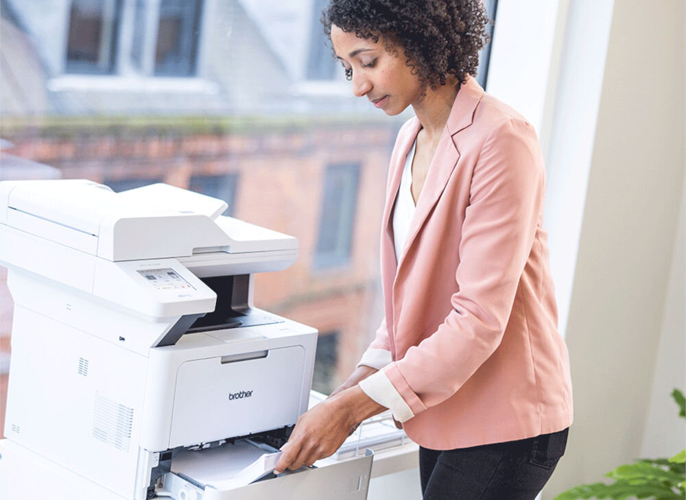 Urządzenie wielofunkcyjne BROTHER MFC-L5710DW Automatyczny druk dwustronny, Wi-Fi prezentacja urządzenia podczas korzystania przez kobietę w biurze elastyczność w połączeniu łączność bezprzewodowa Wi-Fi pasma 2,4 5 GHz port USB Ethernet