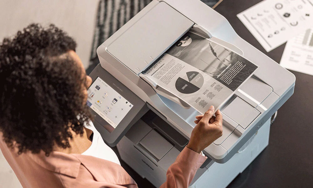 Urządzenie wielofunkcyjne BROTHER MFC-L6910DN Automatyczny druk dwustronny prezentacja urządzenia w biurze na szafce kobieta korzystająca z niego zdjęcie od góry