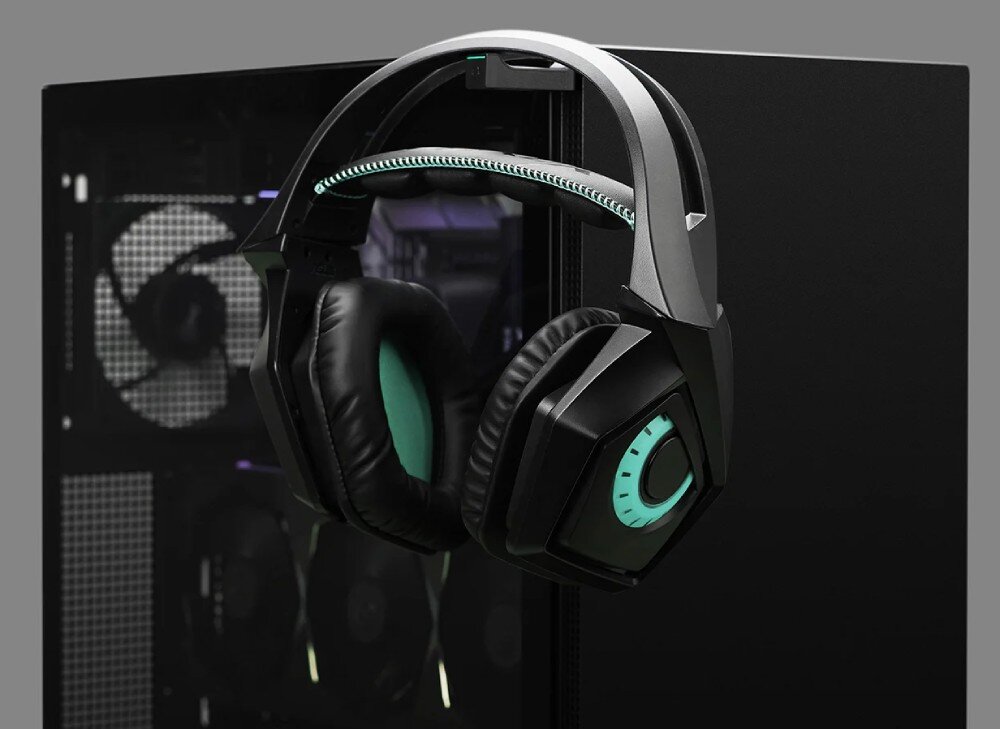 Obudowa DEEPCOOL CH510 Duże czarne słuchawki nauszne zawieszone na wysuwanym uchwycie, który znajduje się na krawędzi przedniego panelu obudowy komputerowej. W tle przez szybę prześwitują podzespoły wewnętrzne
