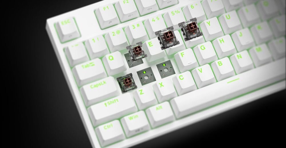 GENESIS Thor 404 TKL stabilizatory fabryczne smarowanie - Zbliżenie na klawiaturę z zielonym podświetleniem i odsłoniętymi włącznikami na niektórych klawiszach.