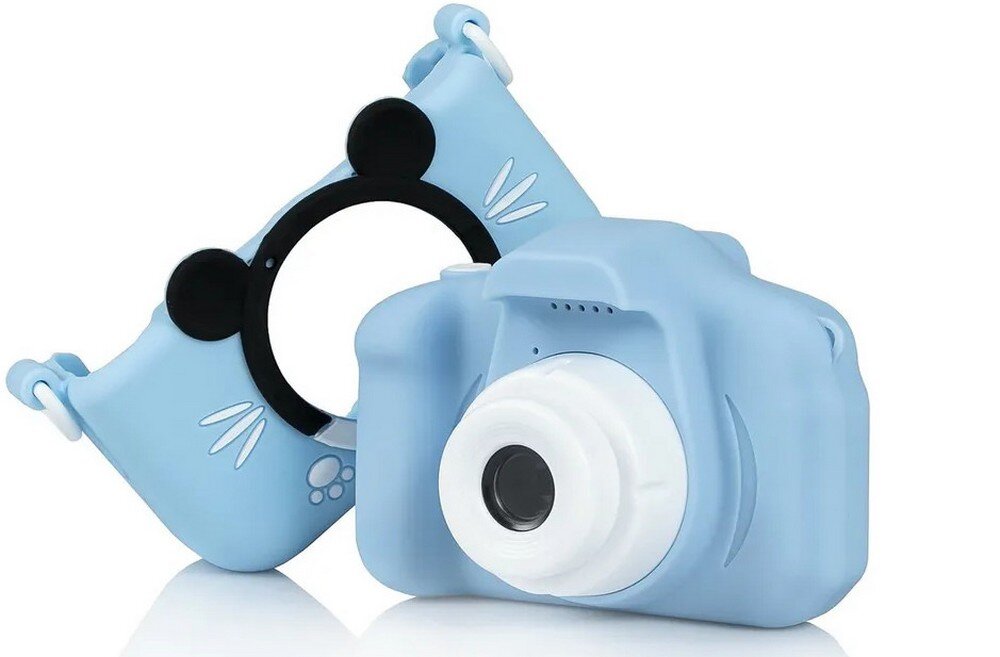 Na obrazie widoczny jest niebieski aparat fotograficzny dla dzieci z białym obiektywem. Obok aparatu znajduje się niebieska osłona z czarnymi uszami i białymi wzorami.