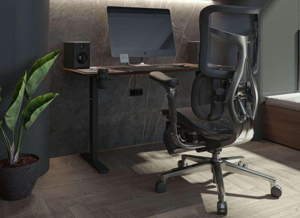 Fotel DIABLO CHAIRS Brave V-Kinetic Czarny prezentacja fotela przy biurku w ciemnym pokoju na biurku monitor z akcesoriami głośniki podnośnik wytrzymałość obciążenie do 120 kg komfort