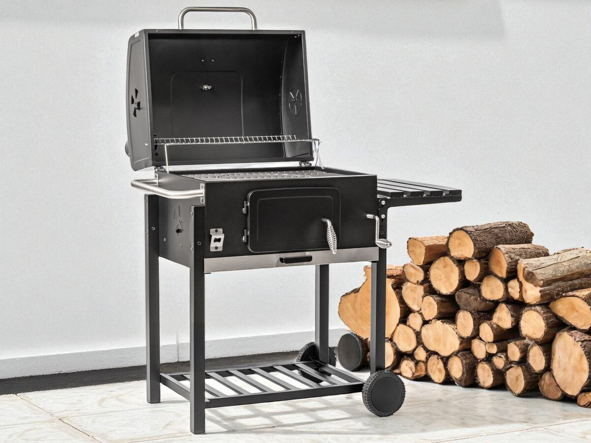 Grill węglowy BBQ LINE MIR4525 z kominem 61 x 45.5 cm, ogród, smażenie, gotowanie, potrawy, grill stoi na tarasie w towarzystwie ściętego drewna
