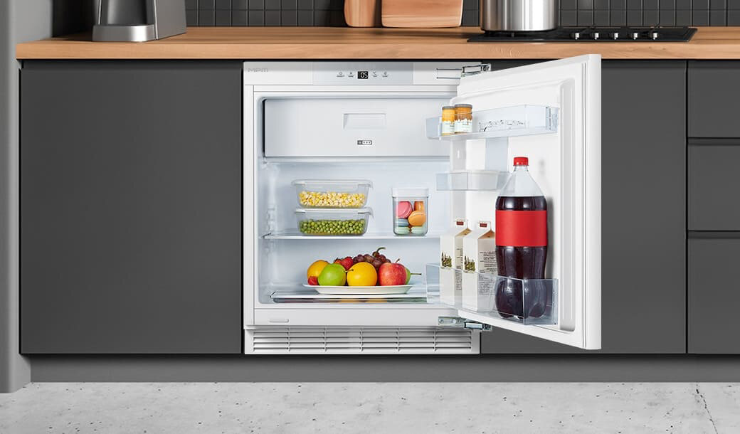 Otwarta lodówka MPM-116-CJI-17/E w ciemnej zabudowie kuchennej.