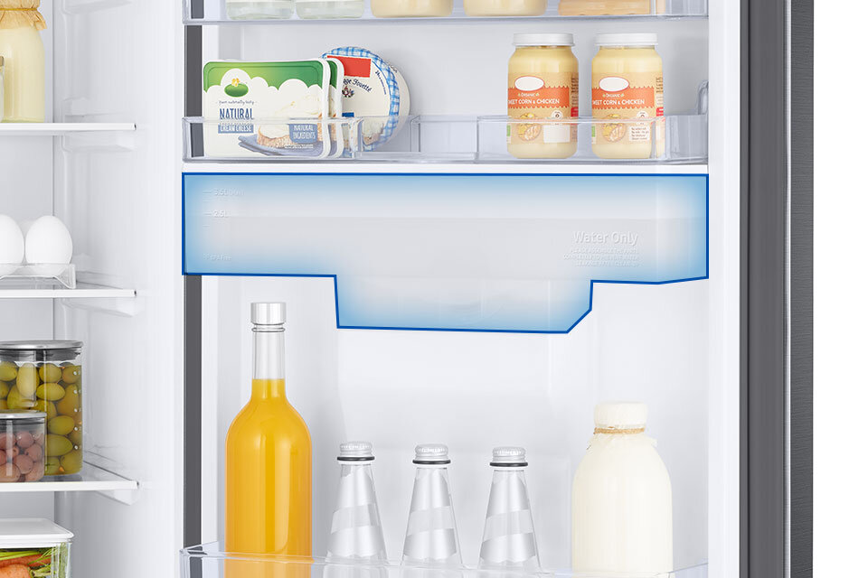 Wnętrze lodówki z półkami wypełnionymi różnymi produktami spożywczymi, takimi jak jajka, słoiki z oliwkami, butelki z napojami oraz opakowania z serem i jogurtem. Na jednej z półek widoczny jest napis \'Water Only\'.