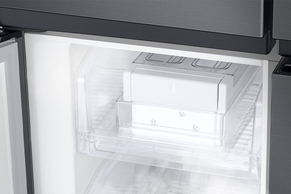 Wnętrze lodówki z widocznym przezroczystym pojemnikiem na kostki lodu. Pojemnik znajduje się na półce, a obok widoczna jest część drzwi lodówki.