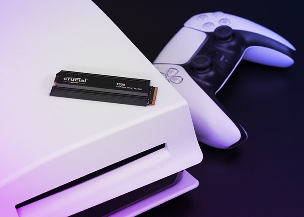 Dysk CRUCIAL T500 Czarny dysk SSD leży na obudowie konsoli do gier obok białego pada, interfejs, zużycie energii, wydajność