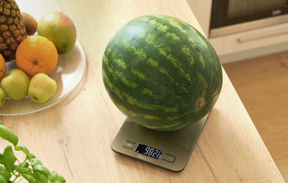 Waga kuchenna SENCOR SKS 8080 Srebrny srebrna waga przyciski wyświetlacz waga leży na blacie na wadze leży arbuz dla miłośników precyzyjnego gotowania zdrowy styl życia technologia Bluetooth integracja z aplikacją SENCOR FOOD monitorowanie nawyków żywieniowych kontrolowanie spożywanych ilości możliwości pomiaru do 10 kg z dokładnością do 1 grama do ważenia składników w dbaniu o zrównoważoną dietę 