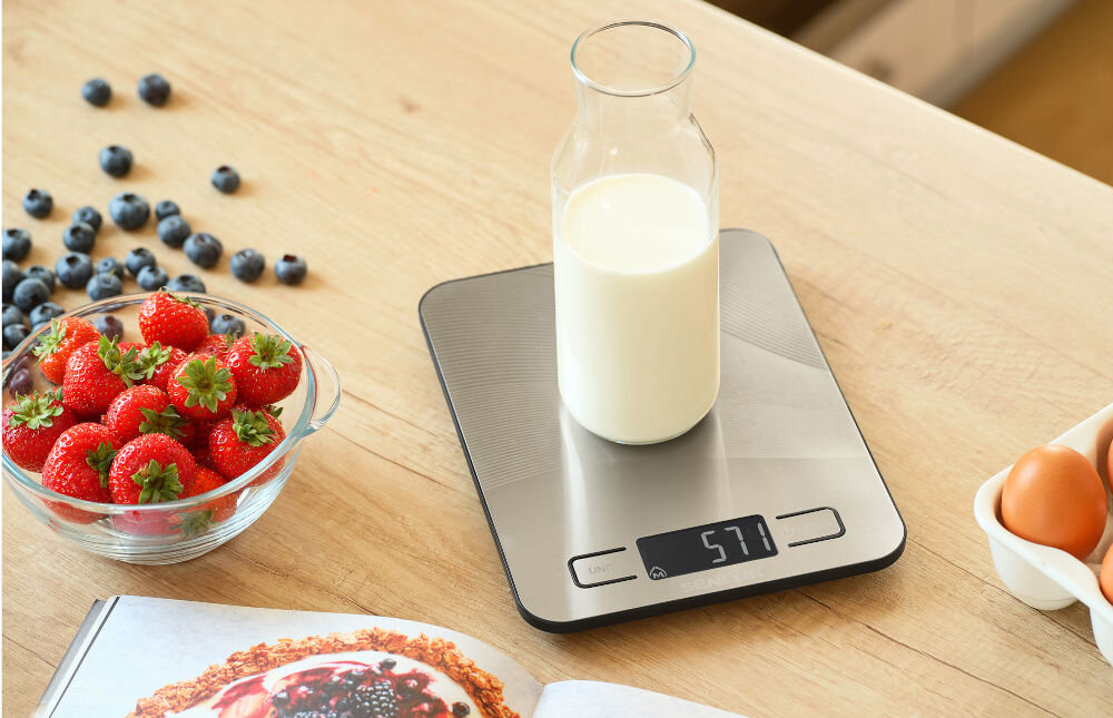 Waga kuchenna SENCOR SKS 8080 Srebrny srebrna waga przyciski wyświetlacz na wadze stoi karafka z mlekiem stylowy srebrny design praktyczny wyświetlacz LCD podświetlany na biało maksymalna nośność do 10 kg zasilanie dwiema bateriami AAA wygoda użytkowania 