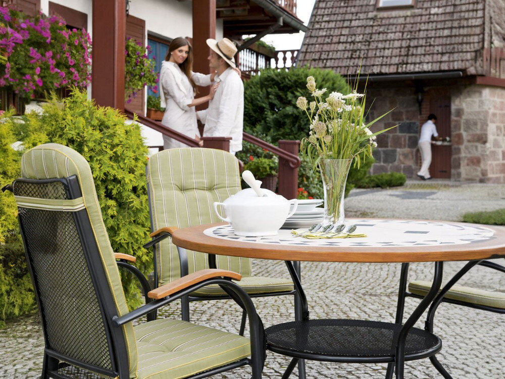 Stół ogrodowy PATIO Como 100 cm Brązowo-beżowy, średnica, osoby, okrągły, spotkania, w tle para na schodach rozmawia, na pierwszym planie stół