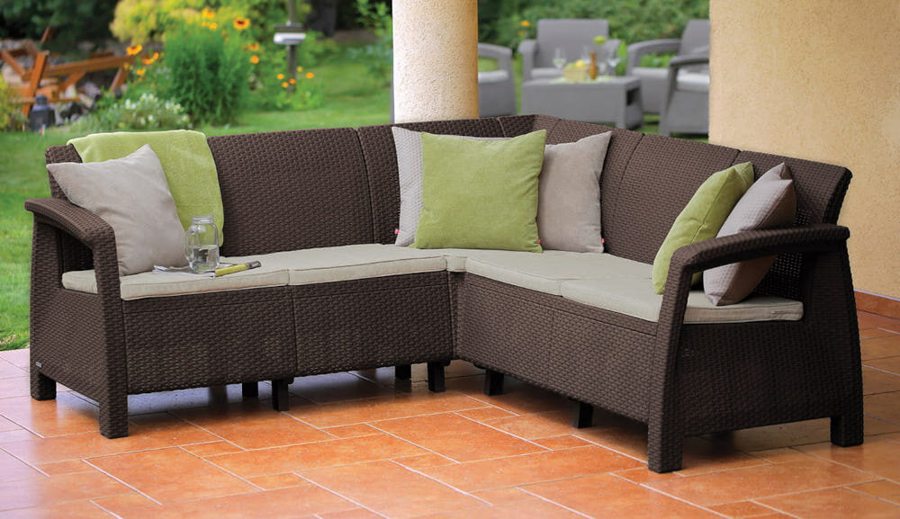 Zestaw mebli ogrodowych KETER Corfu II Relax Brown 258949 narożnik na tarasie w tle rośliny i trawnik narożnik odpowiednie warunki do spokojnego relaksu wymiar 190 x 190 x 79 cm obciążenie do 550 kg