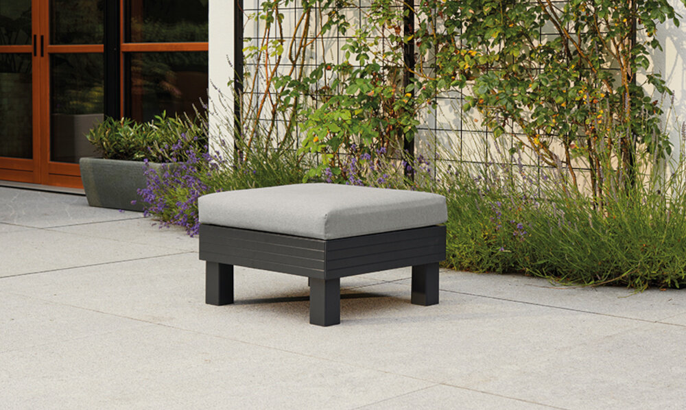Pufa ogrodowa KETER Elements Single Hocker 257368 Grafitowo-szary pufa na tarasie w tle dom i rośliny elastyczne wyposażenie ogrodu relaks spotkania z rodziną znajomymi modułowa forma