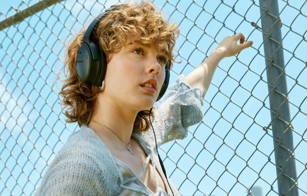 Słuchawki nauszne BOSE QuietComfort ANC główne cechy produktu, osoba z założonymi słuchawkami nausznymi