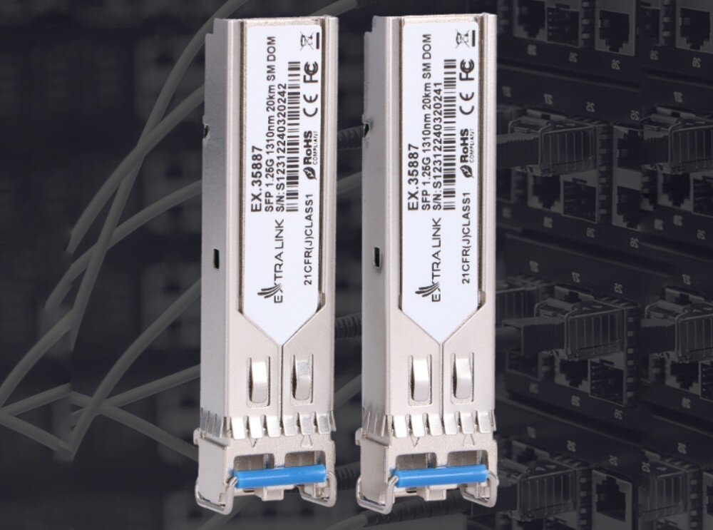 Wkładka SFP EXTRALINK EX.35887 (2 szt.) Dwa identyczne srebrne moduły sfp z niebieskimi uchwytami pokazane od strony etykiet na ciemnym, rozmytym tle przedstawiającym szafę serwerową z okablowaniem