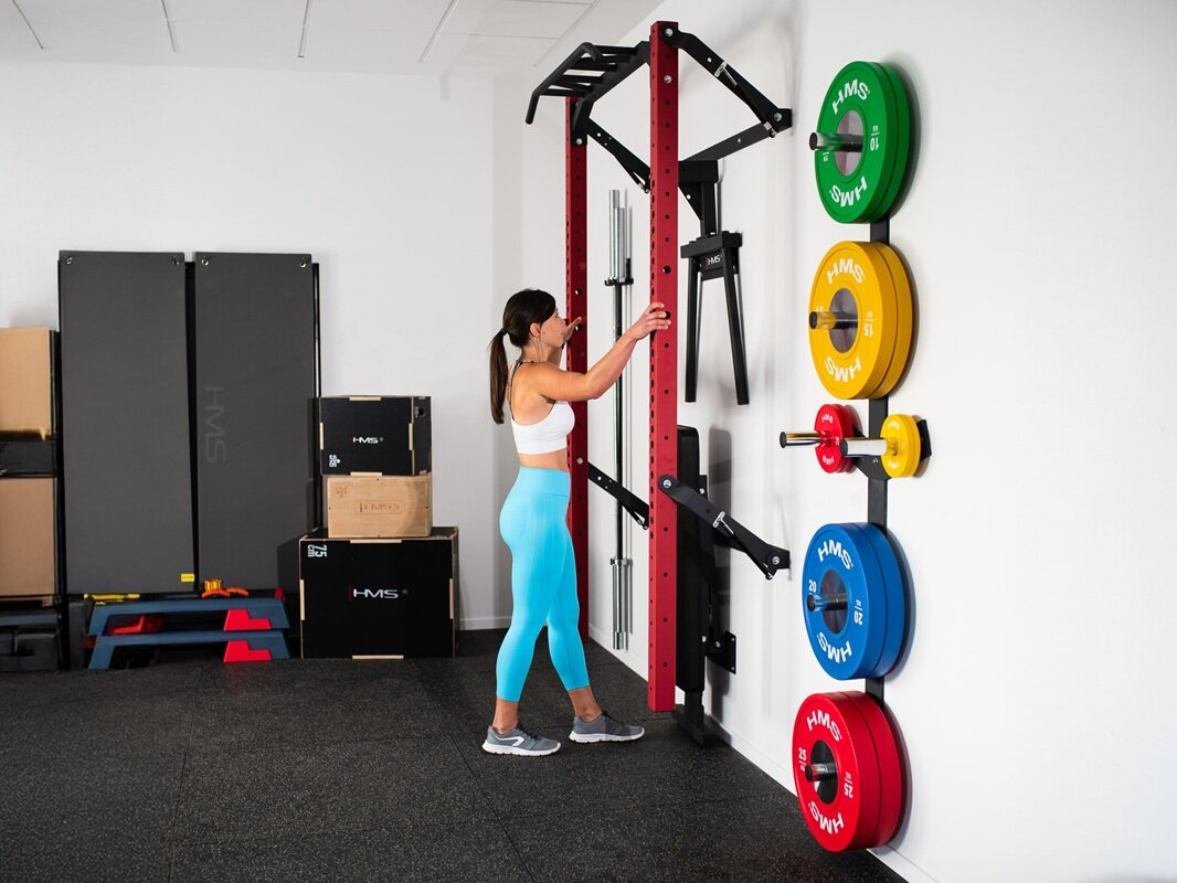 Klatka treningowa HMS KLT22 Czerwony dziewczyna składa klatkę dookoła są produkty Hms do ćwiczeń takie jak: maty fitness, stepy, skrzynie plyometryczne oraz talerze bumper wielofunkcyjna stabilną bazę do pracy nad siłą, sylwetką i kondycją montaż do ściany przemyślany zestaw akcesoriów