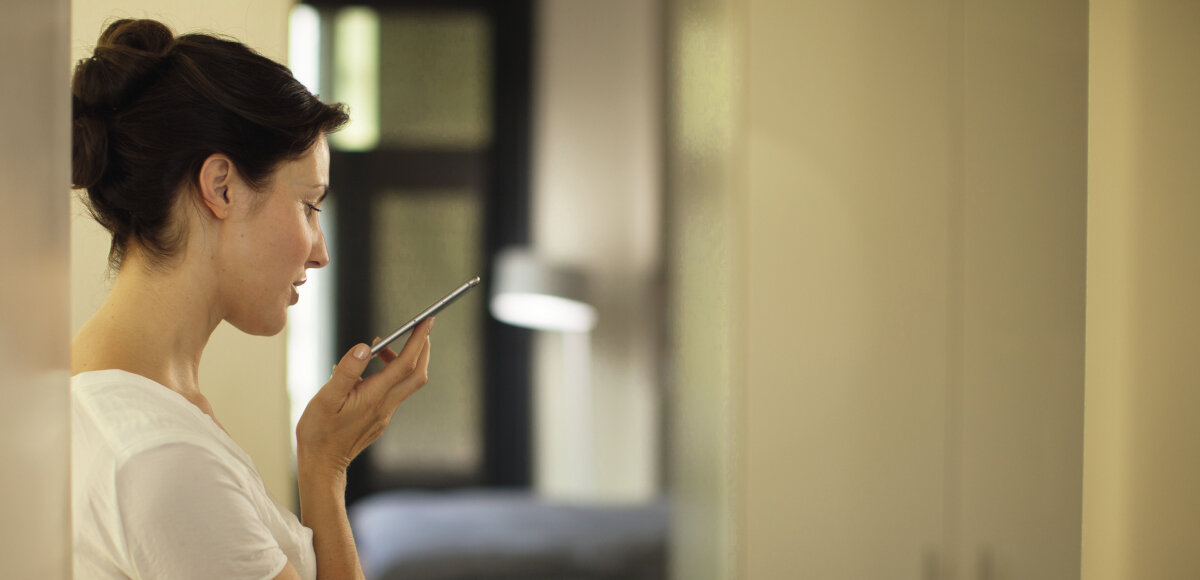 Girlanda PHILIPS HUE Festavia 250 świateł, aplikacja, sterowanie, mobilne, głosowe, Kobieta trzyma w dłoni telefon i steruje głosowo oświetleniem