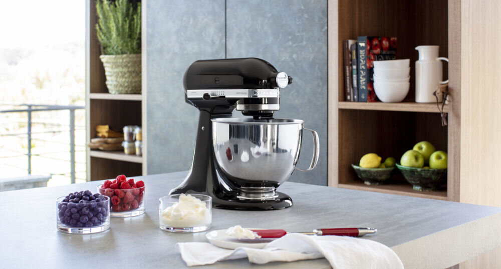 Robot kuchenny planetarny KITCHENAID Artisan 5KSM125EBM 300W czarny robot stoi bokiem na blacie srebrna misa suwak na obudowie owoce w miseczkach z wytrzymałego odlewu cynkowego stabilność urządzenia regulacja prędkości od 58 do 220 obrotów na minutę dostosowanie pracy miksera waży około 10,5 kg długość przewodu zasilającego wynosząca 1,45 m dla amatorów i doświadczonych kucharzy