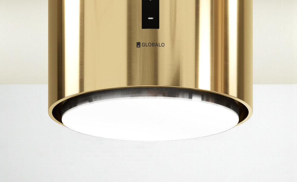 Okap GLOBALO Heweno Isola 39.2 złoty Zdjęcie przedstawia zbliżenie na dolną część cylindrycznego okapu kuchennego marki GLOBALO, z wyraźnie widocznym, okrągłym panelem LED odpowiadającym za równomierne, jasne oświetlenie powierzchni roboczej. Widoczny jest minimalistyczny design oraz dotykowy panel sterowania oświetlenie led naturalne światło komfort gotowania widoczność w kuchni gotowanie wieczorne energooszczędne oświetlenie led okap oświetlenie kuchenne