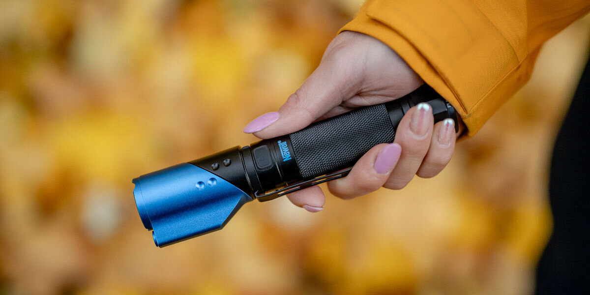 Latarka taktyczna NEWELL FL1000LUV USB-C z UV i laserem, IP54, szczelności, woda, upadki, odporność, Latarka Newell FL1000LUV trzymana w dłoni