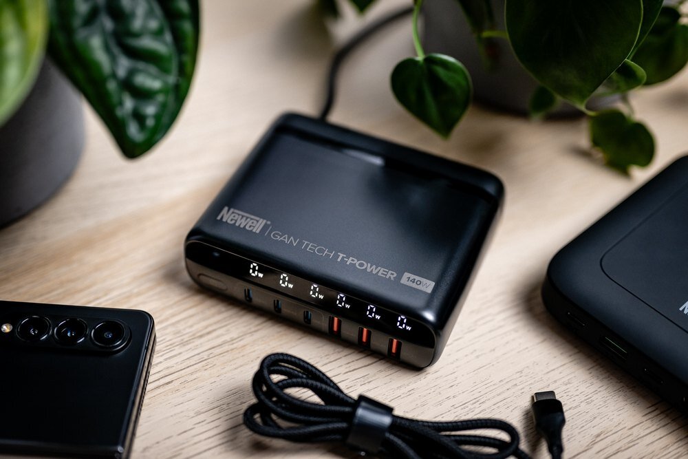 Newell GaN Tech T-power 140 W na stole z innymi urządzeniami obok