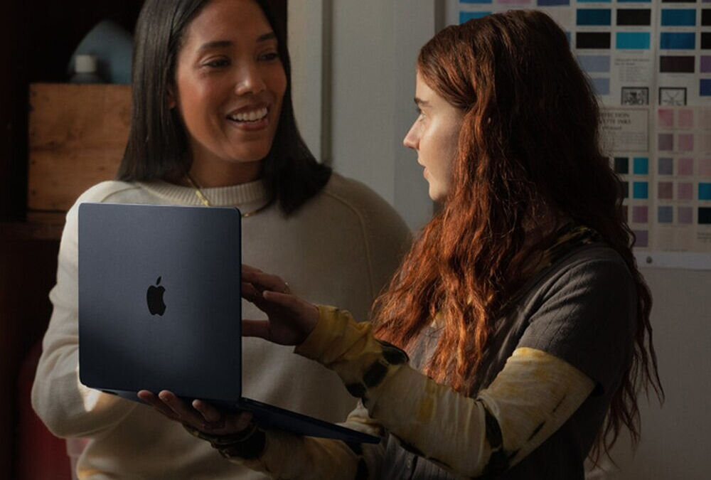 Laptop APPLE MacBook Air 2023 15.3 Retina M2 8GB RAM 512GB SSD macOS Gwiezdna szarość
					smukła i lekka konstrukcja, łączy elegancki wygląd z wysoką mobilnością,
					smukła obudowa z aluminium o grubości ok. 1,15 cm, waga ok. 1,51 kg,
					kobieta trzymająca laptop w trakcie rozmowy z drugą kobietą