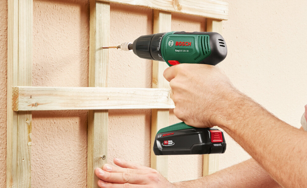 Wiertarko-wkrętarka BOSCH EasyDrill 18V-38 06039D8003 dom ogród osoba przykręca drewnianą konstrukcję do ściany domu silnik szczotkowy prędkość obrotowa do 1630 obr./min sprawne wiercenie efektywne wkręcanie maksymalny moment obrotowy 38 Nm dobra kontrola nad siłą dokręcania
