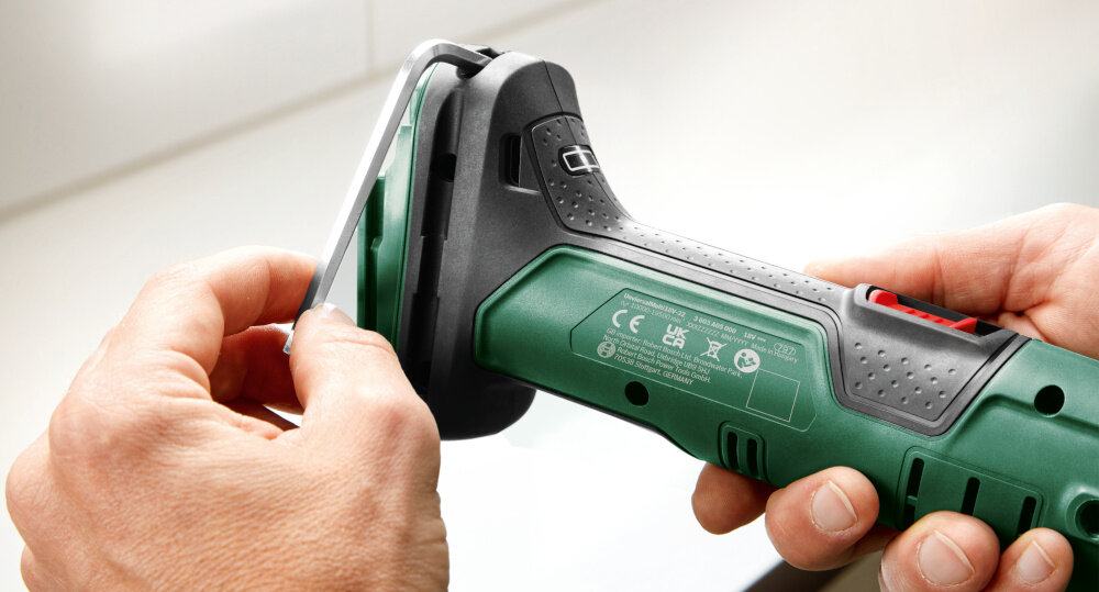 Narzędzie wielofunkcyjne BOSCH UniversalMulti 18V-32 pomieszczenie osoba trzyma narzędzie w dłoni wyciąga z obudowy klucz sześciokątny funkcja MagnetHold utrzymuje akcesoria w stabilnej pozycji klucz sześciokątny pewne mocowanie odpowiednie tempo pracy komfort użytkowania