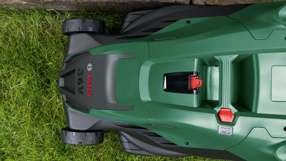 Kosiarka akumulatorowa BOSCH AdvancedlRotak 36V-44-750 06008B9G00 ogród trawnik zbliżenie na przód kosiarki kosiarka kosi trawę przy brzegu ogrodzenia specjalne grzebienie umieszczone przy korpusie pomagają doprowadzić źdźbła trawy pod nóż dokładne koszenie wzdłuż krawędzi trawnika przy murach i innych przeszkodach