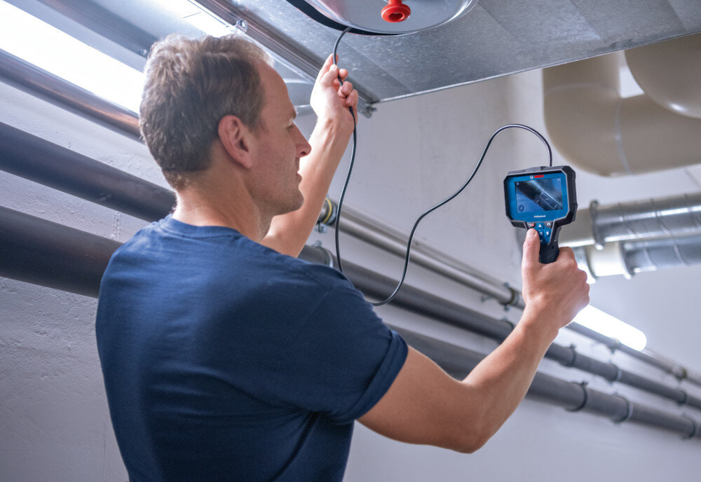 Kamera inspekcyjna BOSCH GIC 12V-5-27C 0601241401 pomieszczenie osoba sprawdza instalację w suficie średnica głowicy kamery wynosi około 8,3 mm elastyczny przewód o długości 150 cm ułatwia lokalizowanie problemów